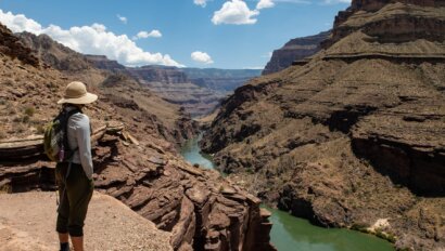 A woman stands on an overlook of the Colorado River in Grand Canyon.