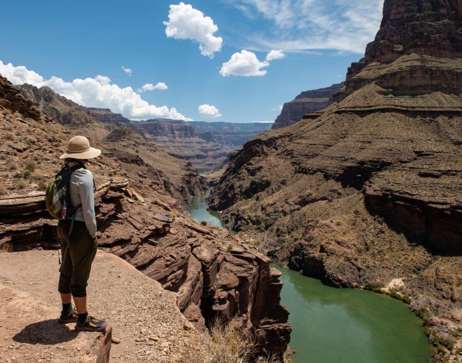 A woman stands on an overlook of the Colorado River in Grand Canyon.