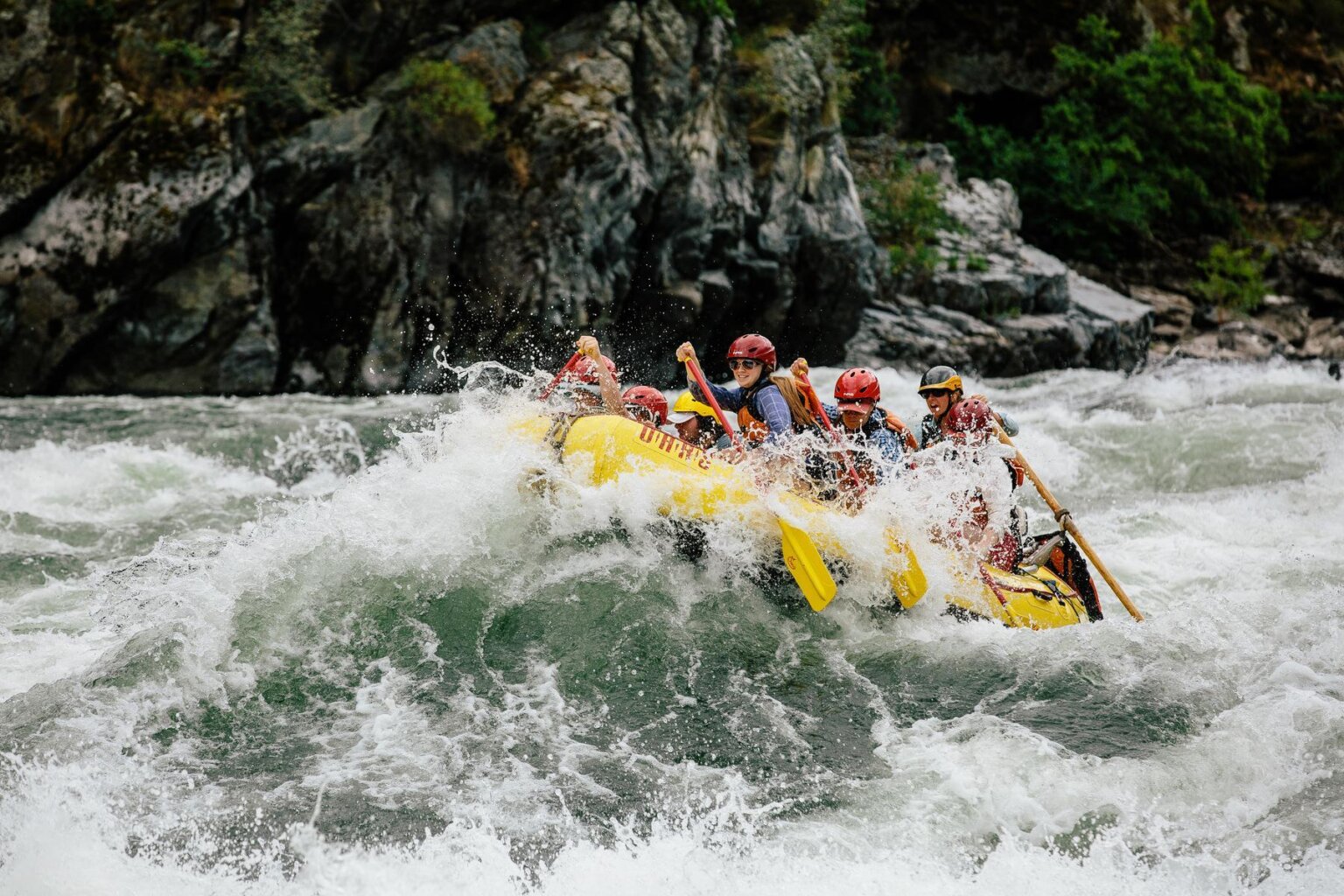 A raft full of guests splashes through a rapid on the Snake River during a rafting trip with OARS.