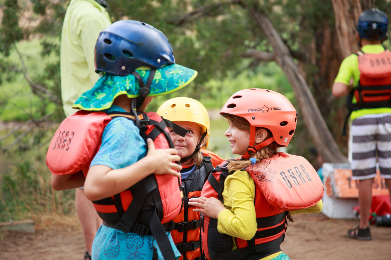 A group of kids in pfds and helmets smile on the Green River.