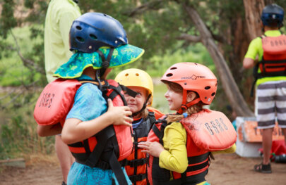 A group of kids in pfds and helmets smile on the Green River.