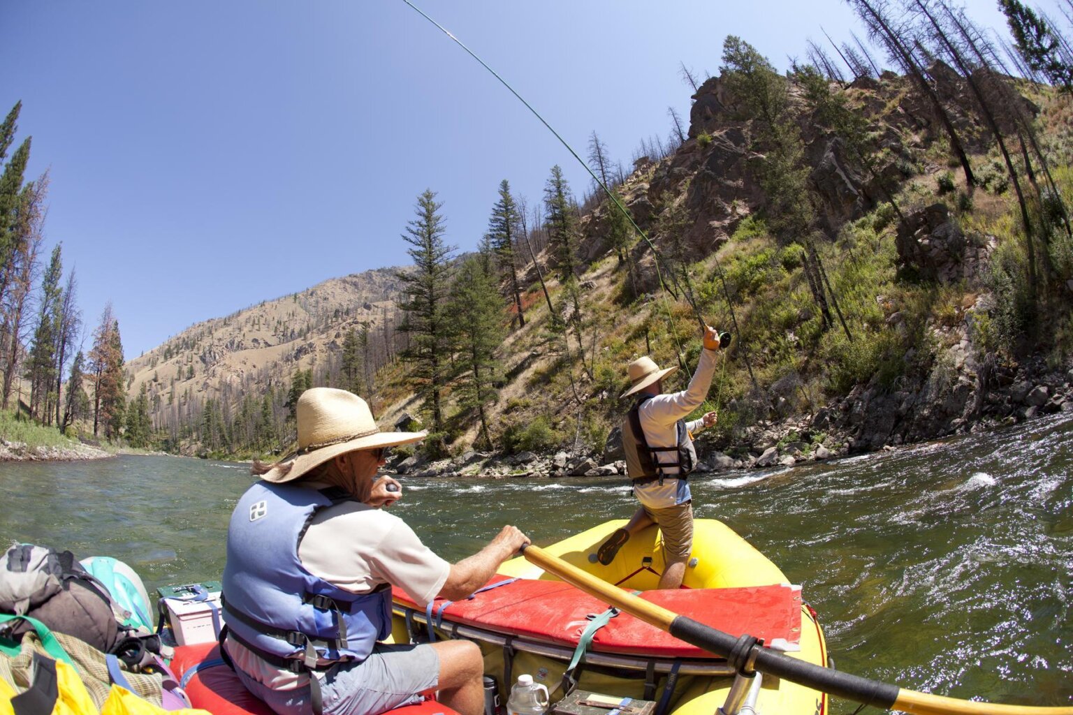 A fly fisherman casts from the front of an OARS raft during a fishing trip on Idaho's Middle Fork of the Salmon River