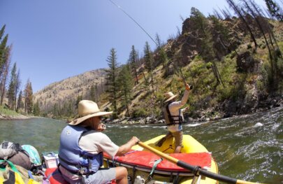 A fly fisherman casts from the front of an OARS raft during a fishing trip on Idaho's Middle Fork of the Salmon River