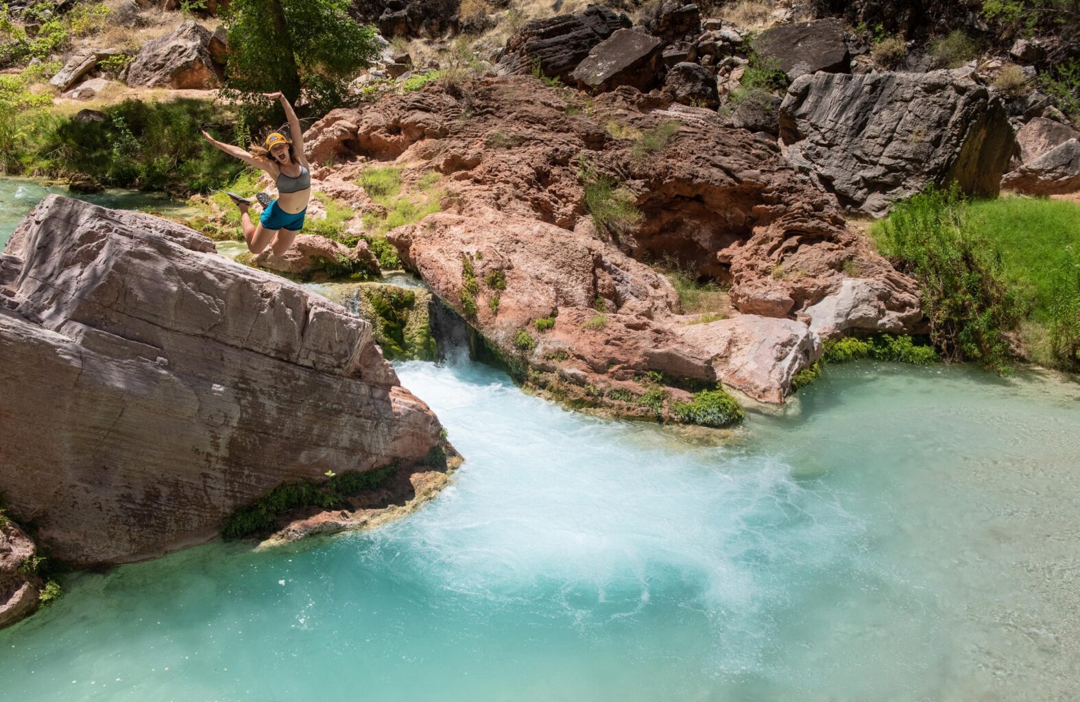 A woman jumps into Havasupai Creek on a Grand Canyon rafting trip with OARS.