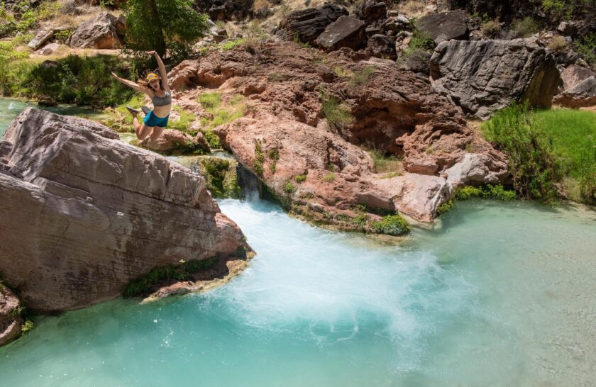 A woman jumps into Havasupai Creek on a Grand Canyon rafting trip with OARS.
