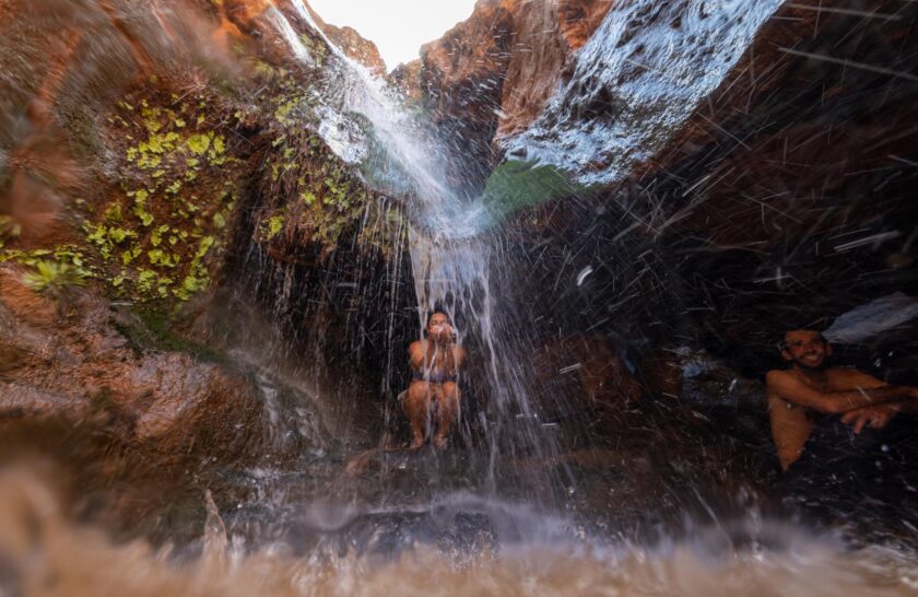 A woman reaches for dripping water in a cavern in a side canyon of Grand Canyon