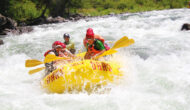 A yellow raft of paddlers surounded by frothy whitewater as they make their way through a rapid on the Tuolumne River in California