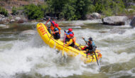 The nose of a yellow raft up in the air as a group of paddlers take on a rapid on the Merced River in California