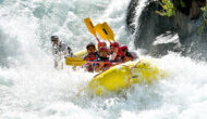 A yellow raft full of paddlers surrounded by frothy whitewater on the Middle Fork of the American River in California