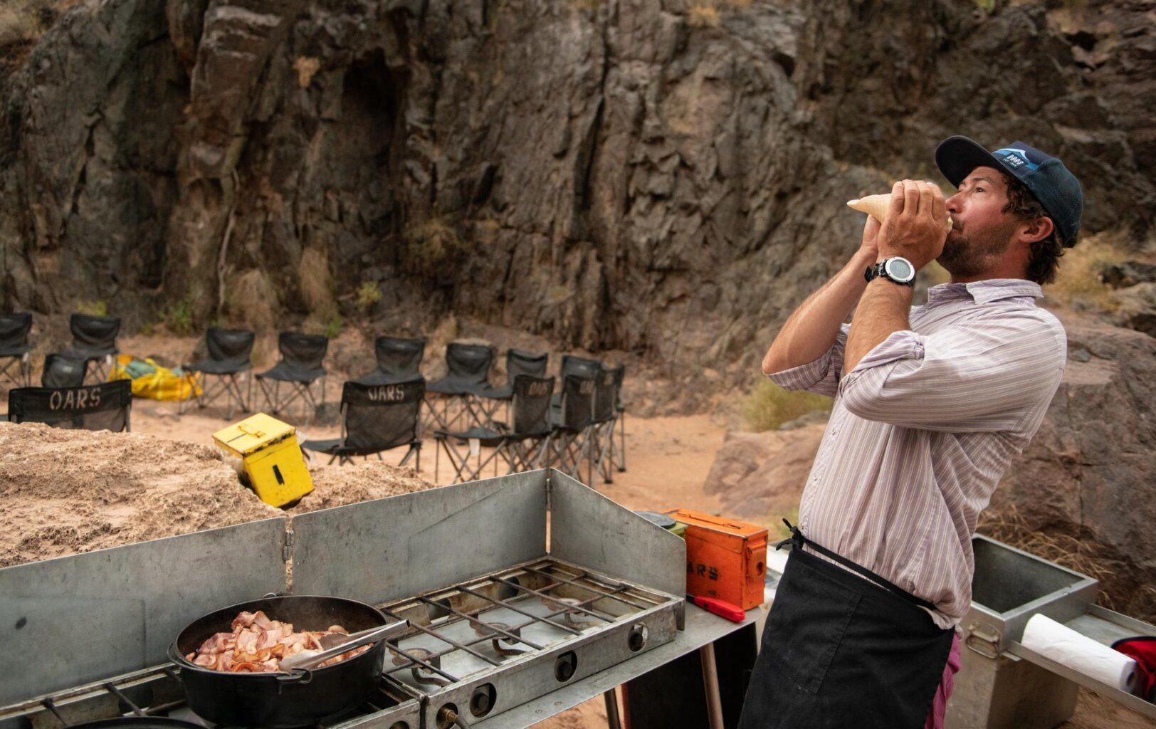 A guide blows the conch for breakfast during a Grand Canyon dory trip with OARS