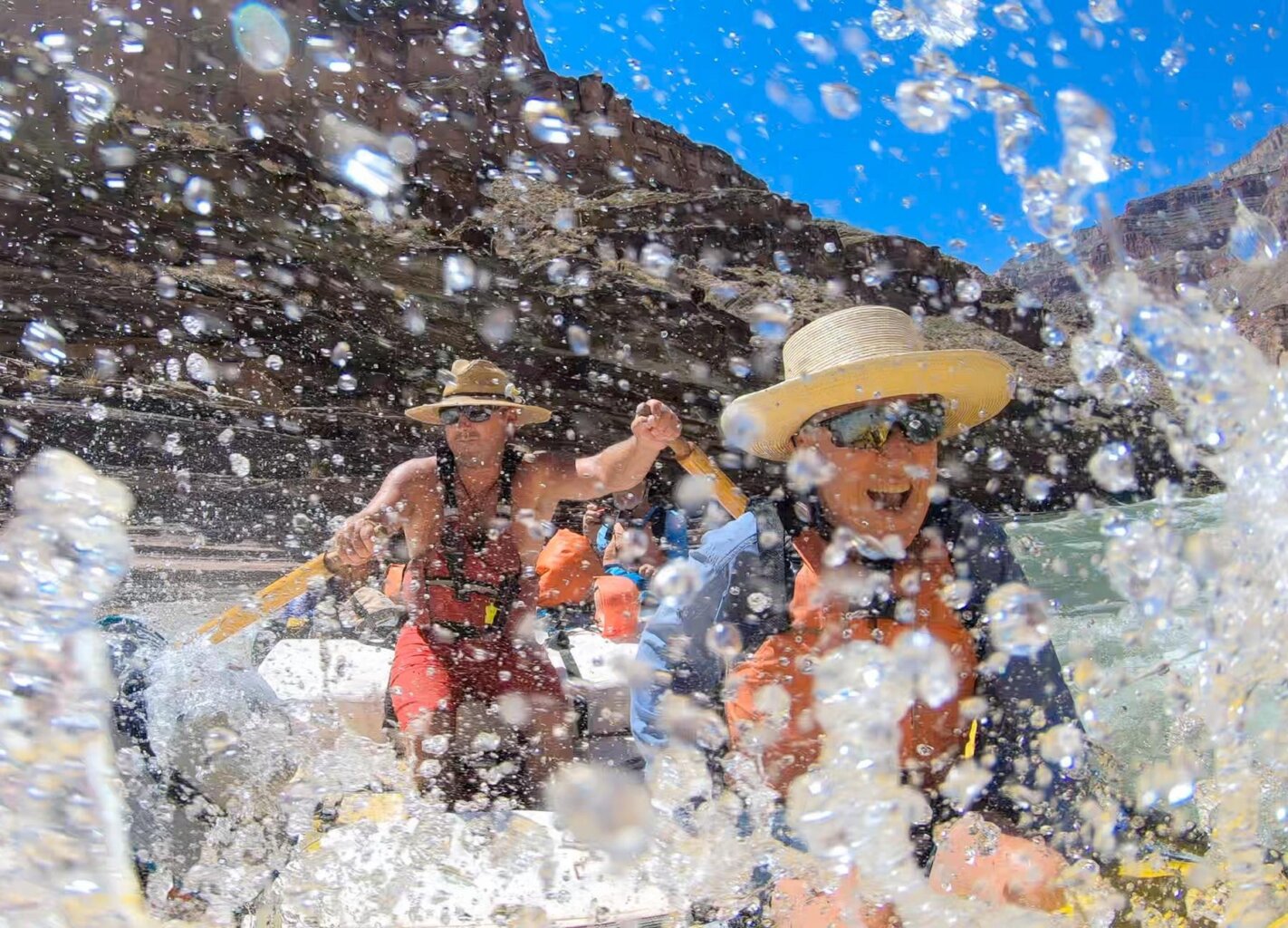 A man smiles as he splashes through a rapid while riding in a guided dory on the Colorado River through Grand Canyon.
