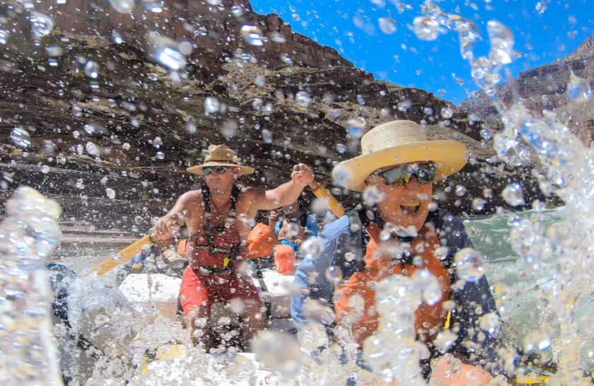 A man smiles as he splashes through a rapid while riding in a guided dory on the Colorado River through Grand Canyon.