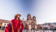 Woman wearing Peruvian blanket stands in front of a building in Cusco, Peru