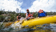 A young person splashes with a paddle during an OARS rafting trip on the South Fork of the American River.