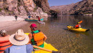 A variety of OARS boats pulling to shore on the Lower Salmon River, including an oar raft, dory, inflatable kayak and dory.