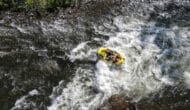 aerial shot of a raft in a river with rapids.