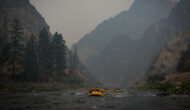 hazy sky over a river with a raft rowing down.