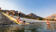 A man sliding down a a makeshift slip n' slide into a river