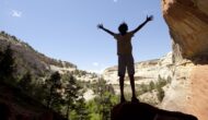 A person raises their arms to celebrate rocks on the Yampa River.