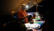 An OARS guide does dishes in the dark on a Grand Canyon rafting trip