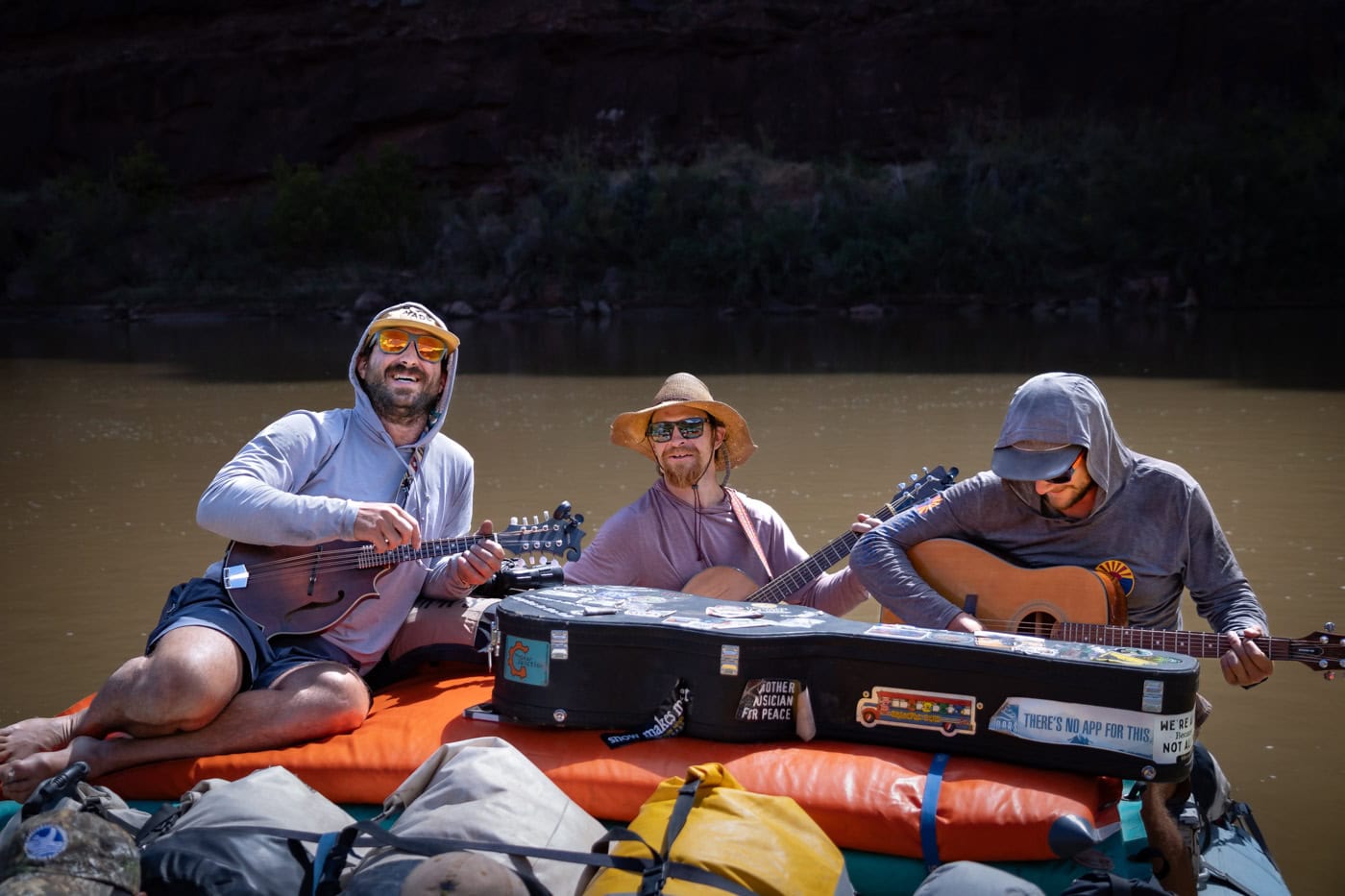 Three river guides play instruments on yellow rafts