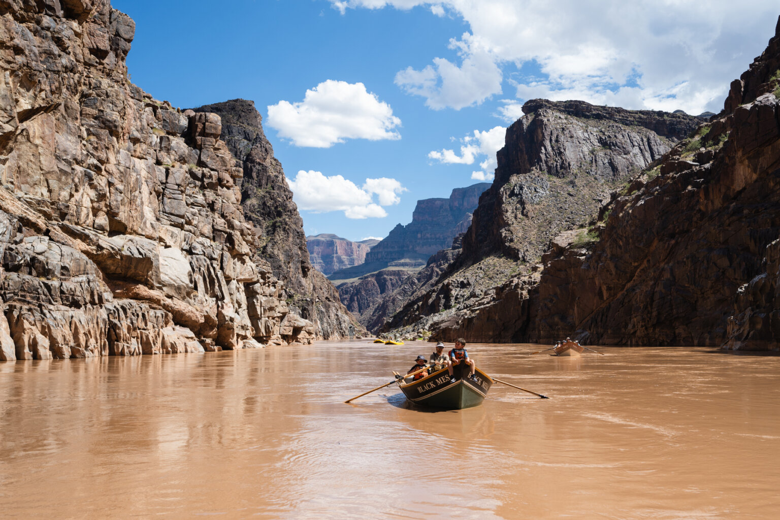 A boy rides the bull of a dory as it makes its way downriver in Grand Canyon