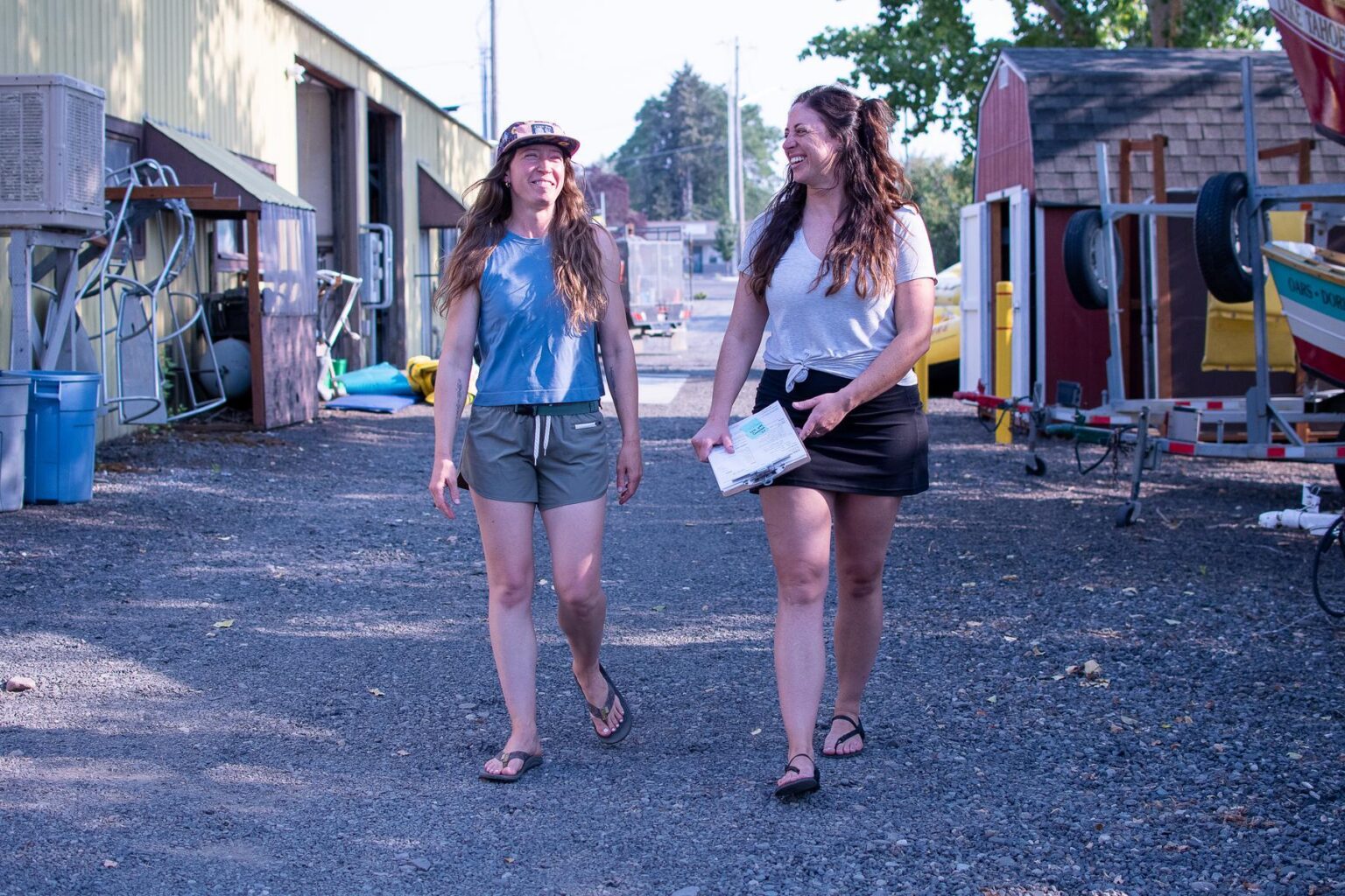 Two women walking side by side outside a rafting warehouse