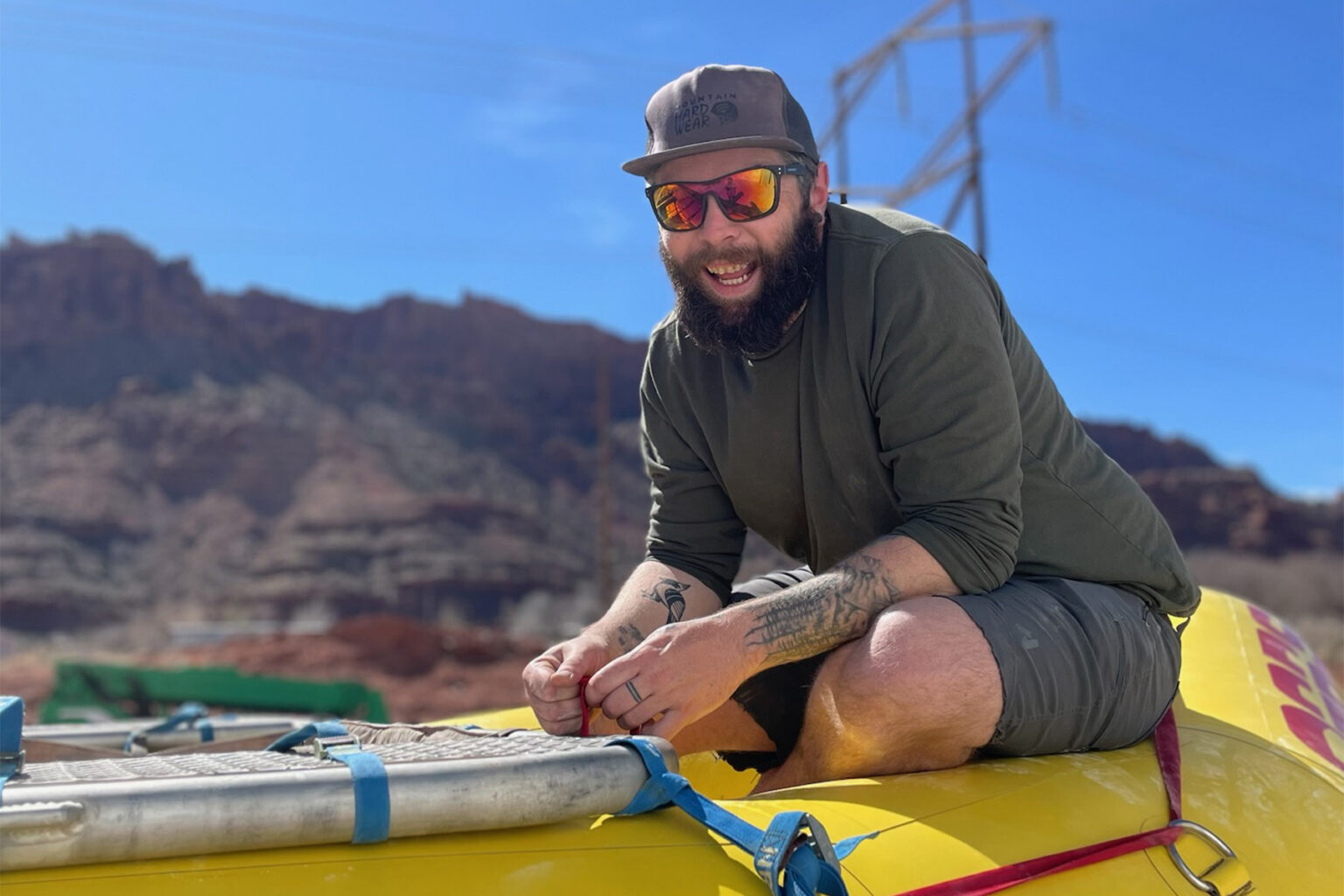 A man sits on top of a yellow raft with red rock canyon scenery in the background