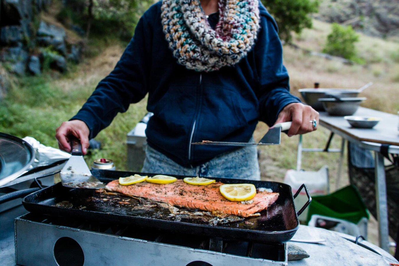 A guide prepares a salmon filet in the camp kitchen on a Hells Canyon trip