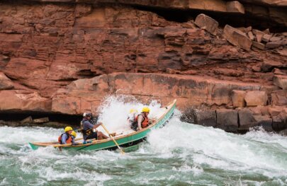 A dory boat goes through a rapid on the Colorado River through Grand Canyon
