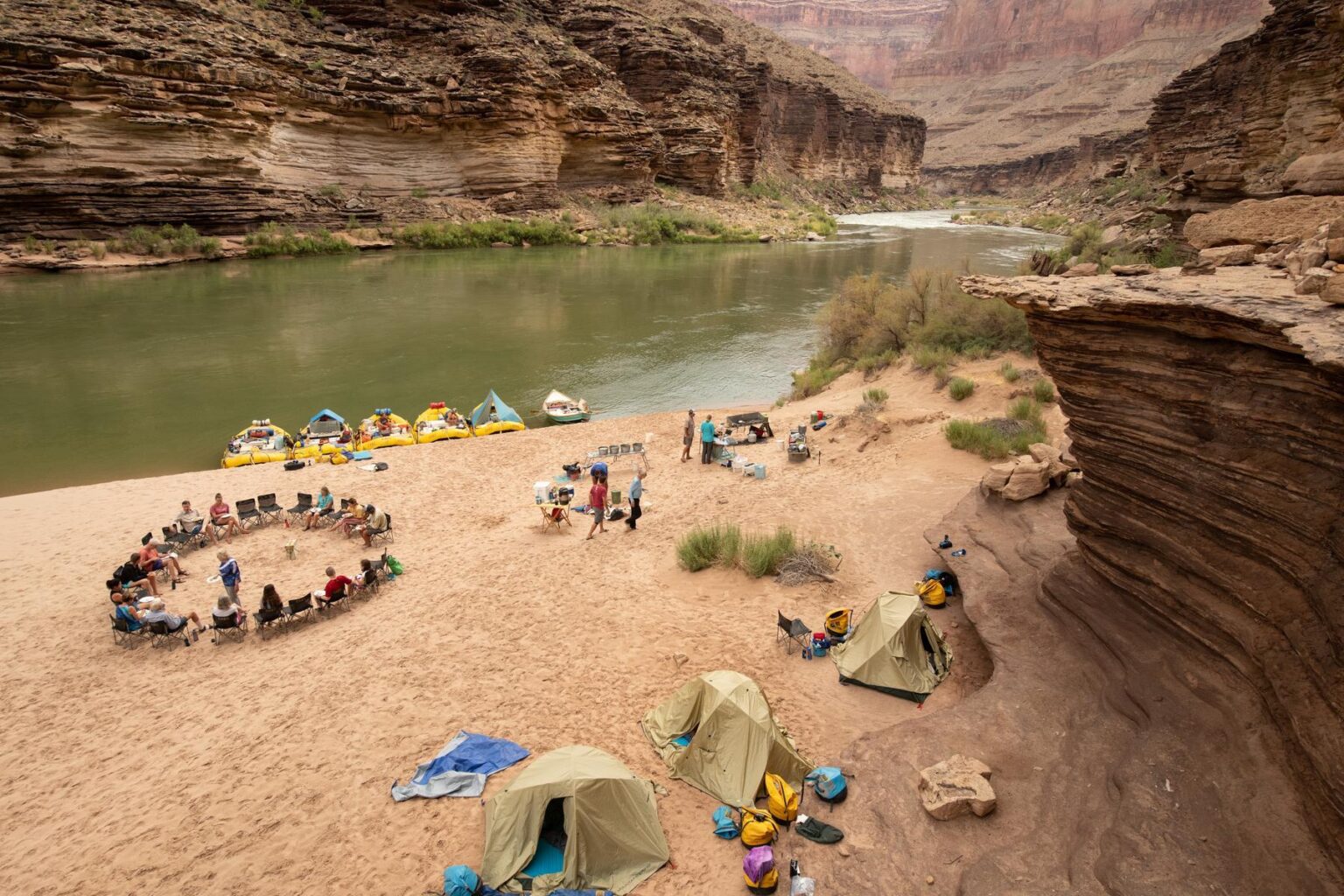 A camp with a chair circle on the banks of the Colorado River in Grand Canyon
