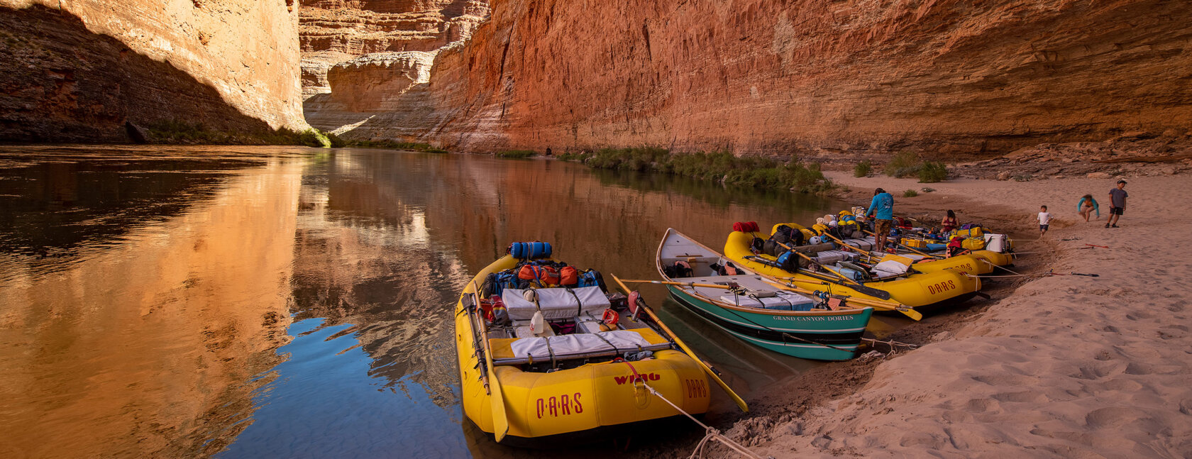 OARS rafts and dories parked on a sandy beach at Redwall Cavern in Grand Canyon