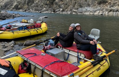 Two women sit on a fishing raft on the banks of Idaho's Middle Fork Salmon River