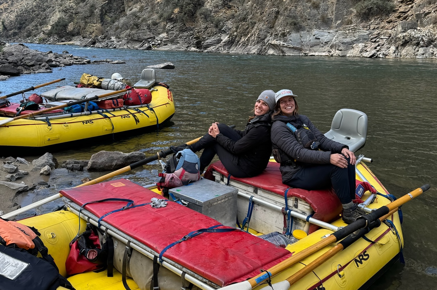 Two women sit on a fishing raft on the banks of Idaho's Middle Fork Salmon River
