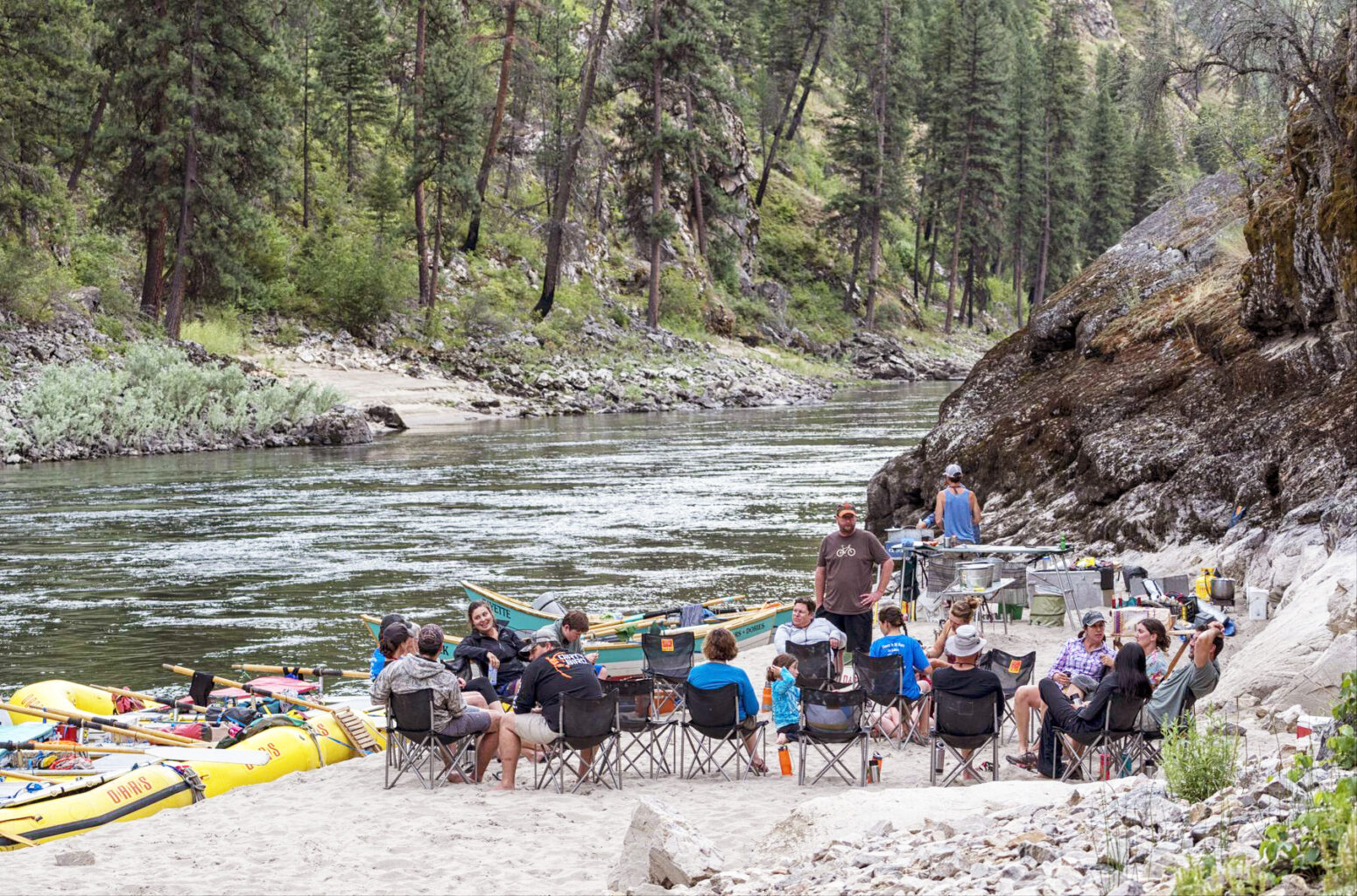 A group gathers in the chair circle at a sandy beach camp along on the Main Salmon River.