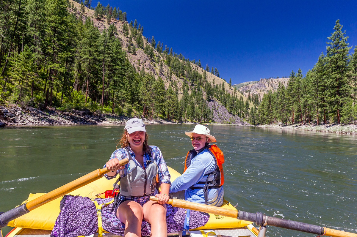A guide and a solo traveler pose for a photo while floating on a yellow raft down the Main Salmon River.