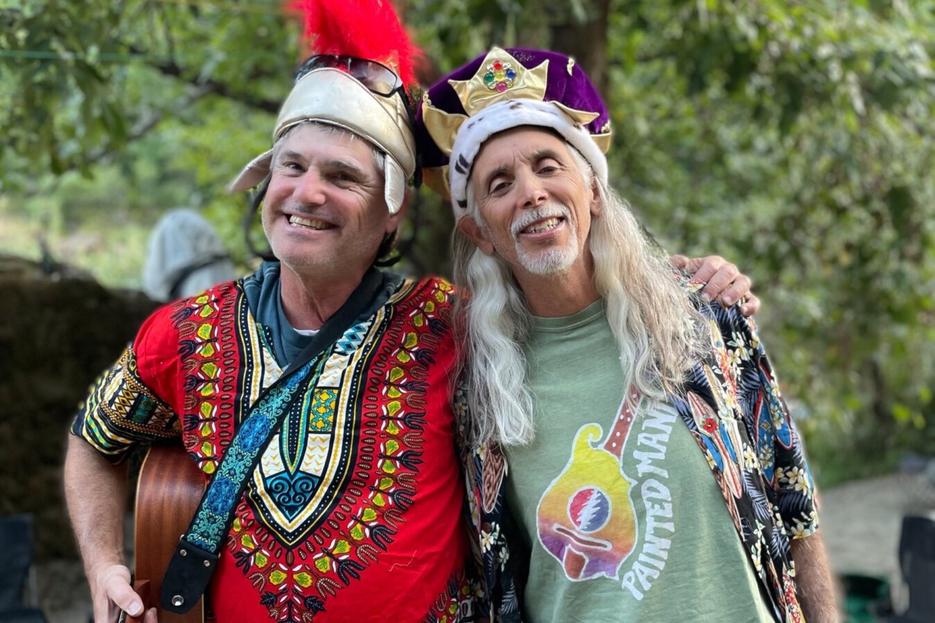 Two men in vibrant and silly costumes smile for the camera while at camp on an OARS river trip.