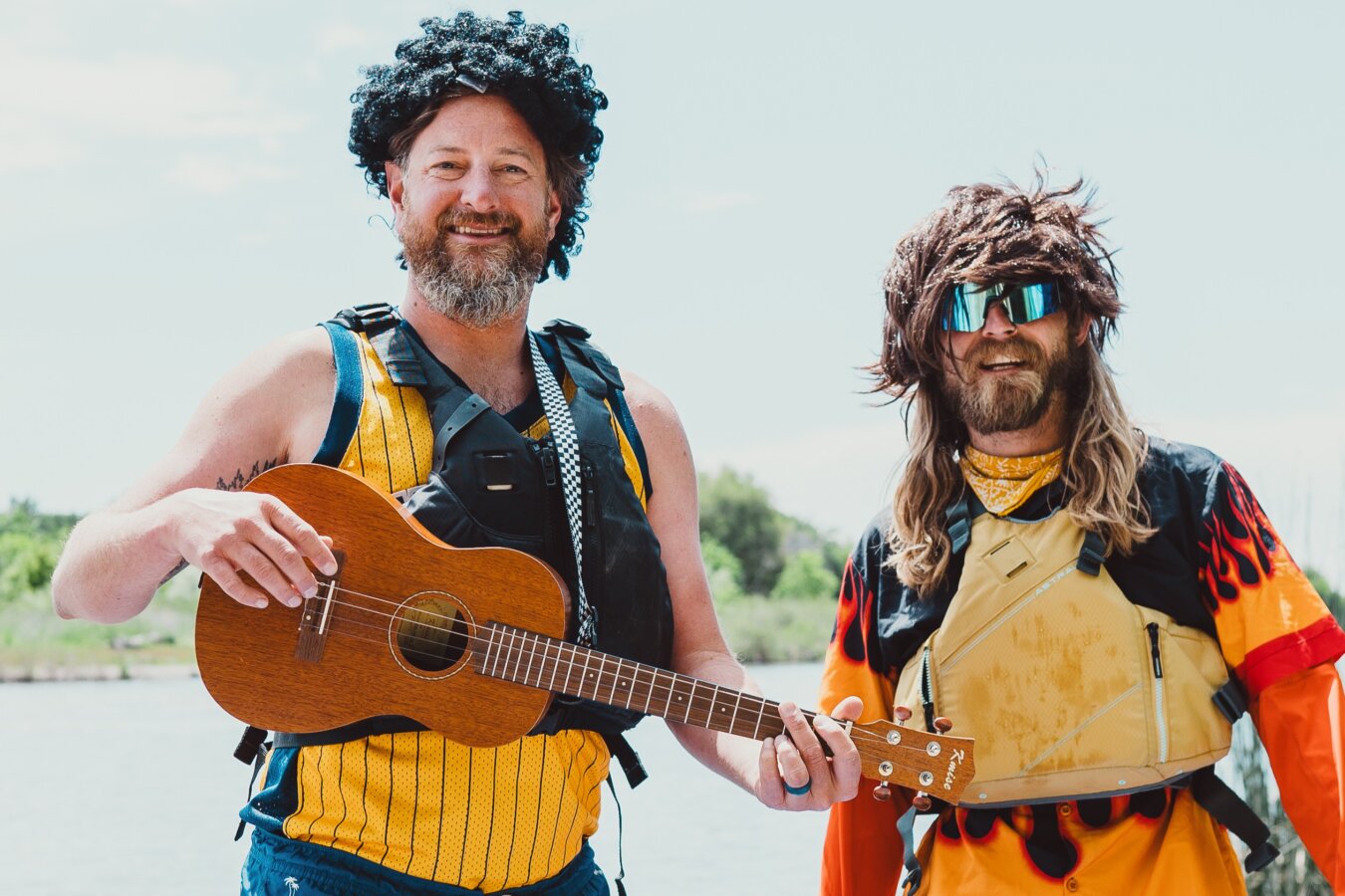 Members of A Brother's Fountain wear wigs and smile at the camera on the river in Idaho