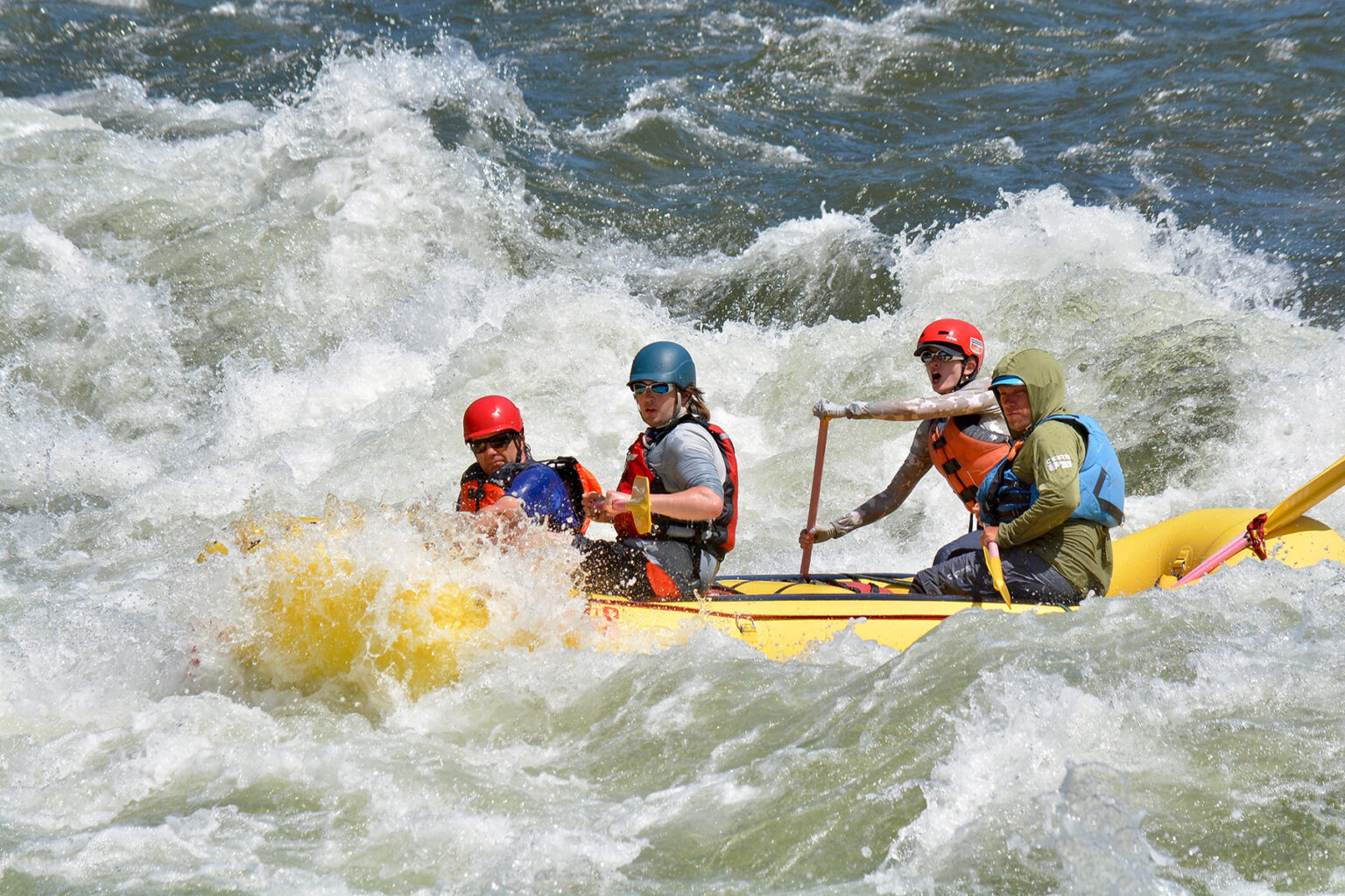 A woman guides a raft full of men through a frothy whitewater rapid on the South Fork of the American River. 